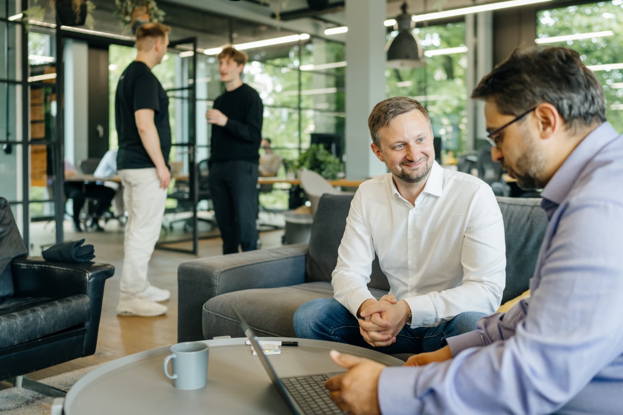 Two Unfuture colleagues in conversation, with other team members working in the background.